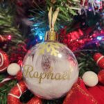 Boule transparente avec plume blanche, écriture prénom en doré.